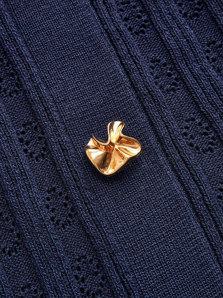 Close-up of a gold sculpted button on the navy denim collar knit dress