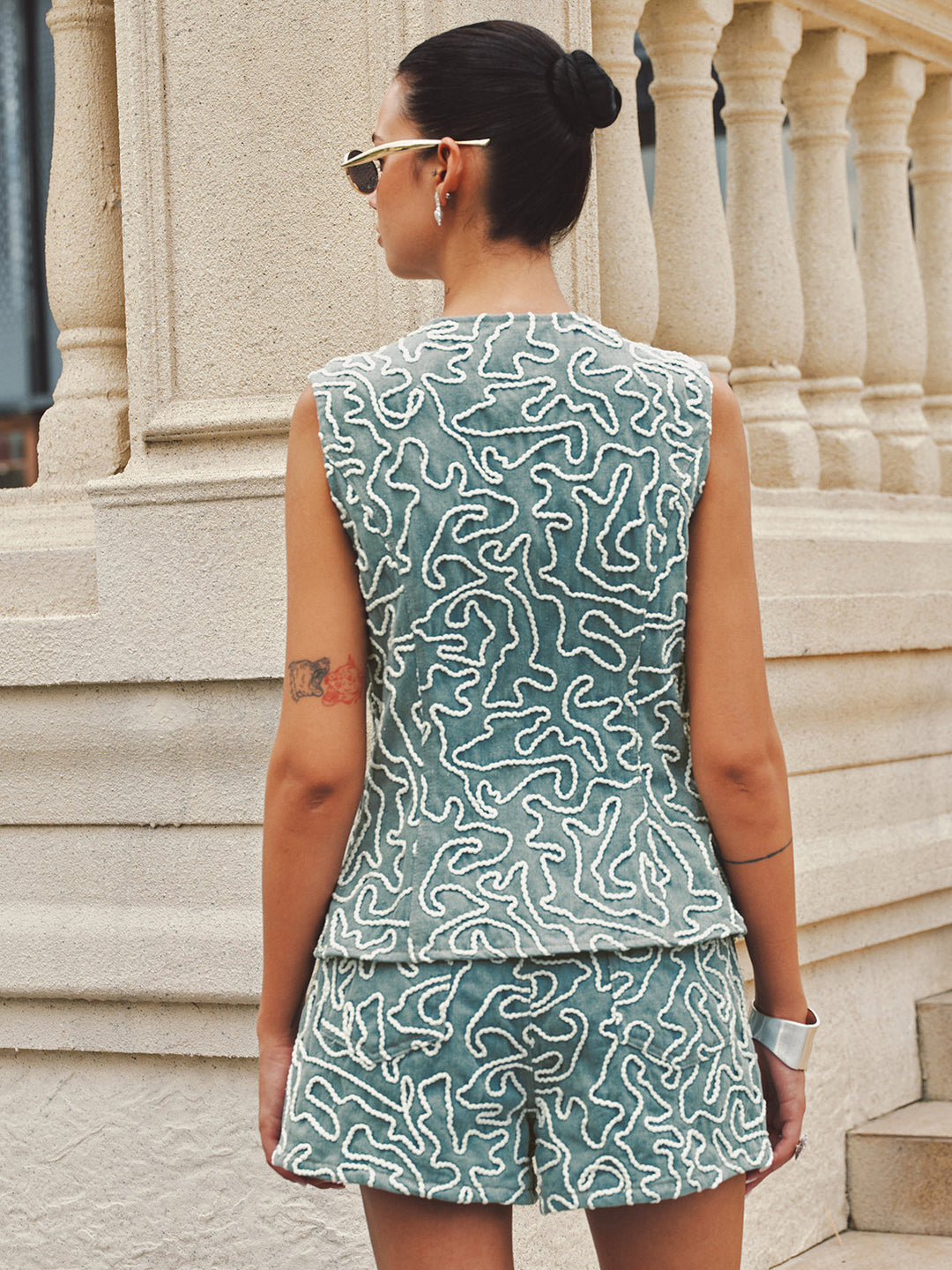 Back view of the sleeveless denim vest and shorts showing the all-over cord embroidery