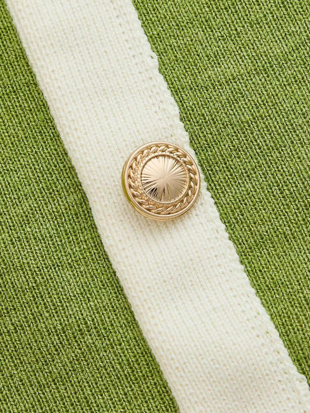 Close-up of the gold rope effect button on the ivory placket of the green knit dress