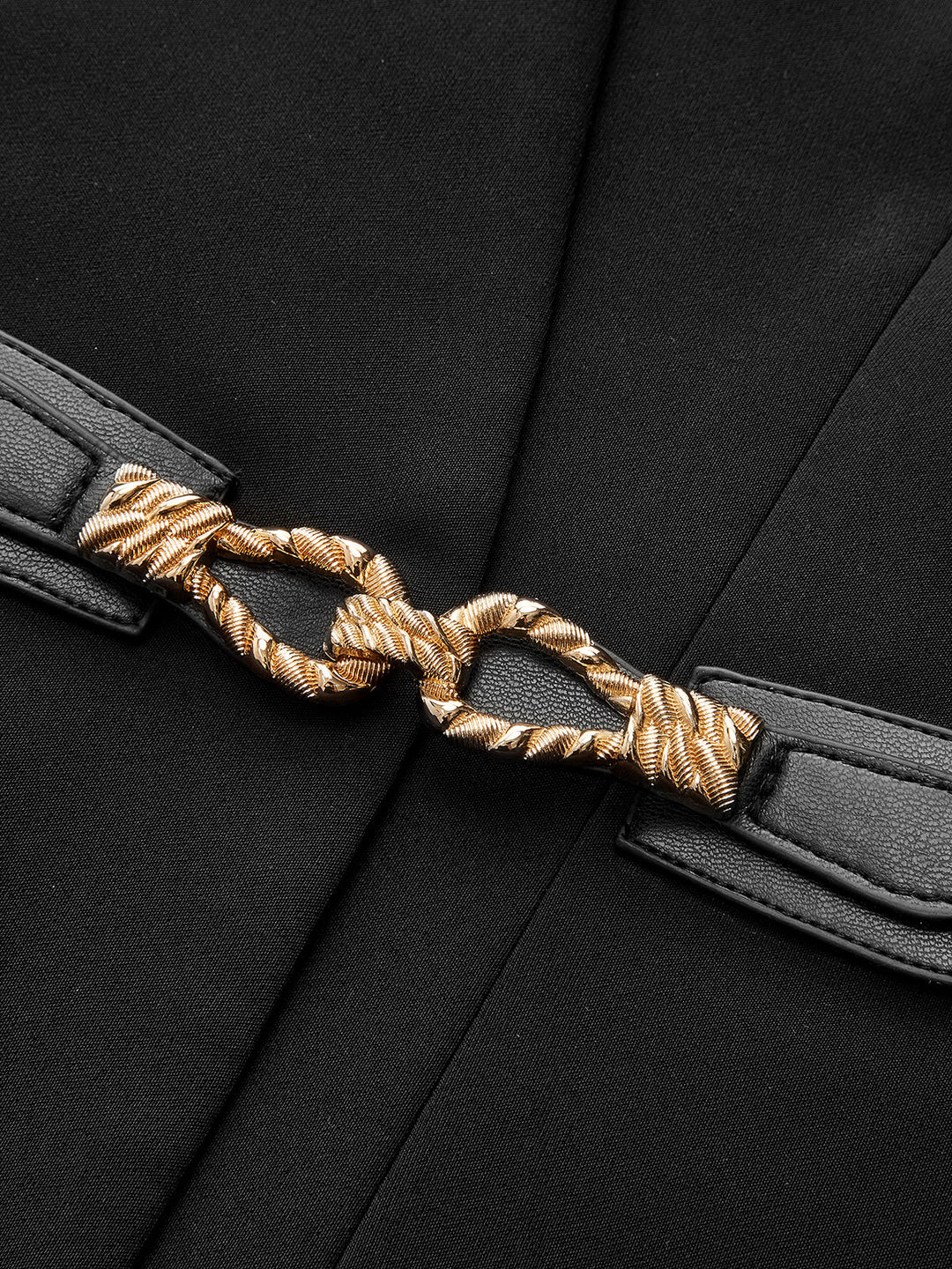 Close-up of twisted gold rope buckle on the black leather waist belt of the sleeveless top