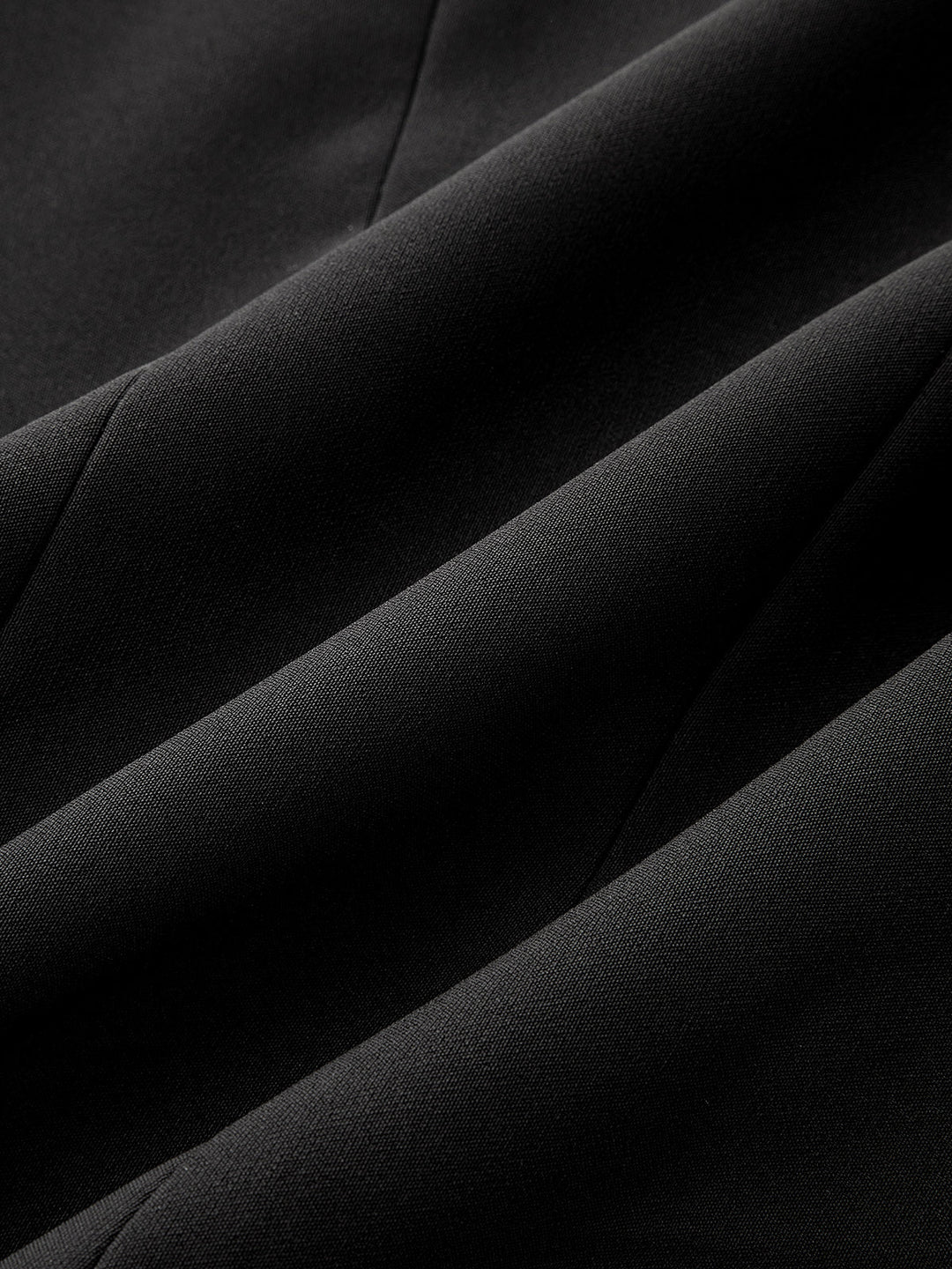 Macro of smooth black crepe fabric used for the metal buckle cinched sleeveless top