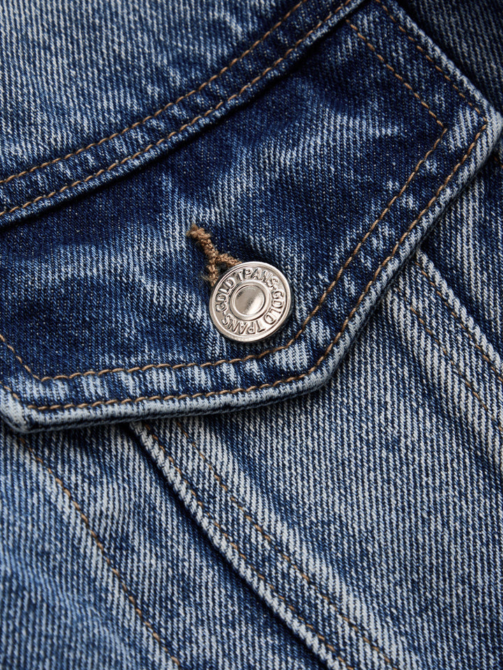 Close-up of the engraved metal button on the denim chest pocket flap