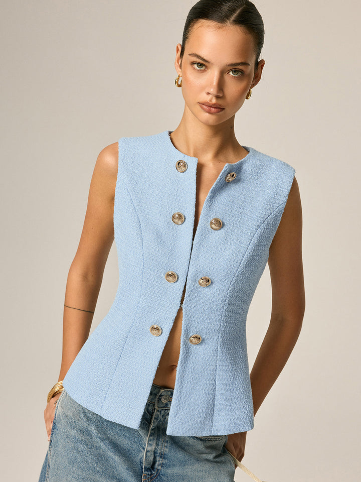 Waist-up portrait of the baby blue tweed vest styled with gold drop earrings and denim