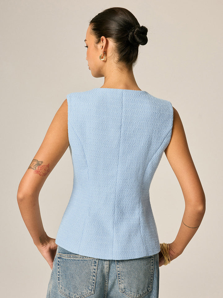 Back view of the pastel blue tweed sleeveless vest worn with light wash jeans