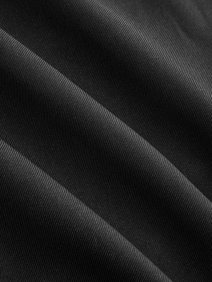 Fabric detail showing the matte black cotton twill of the military jacket