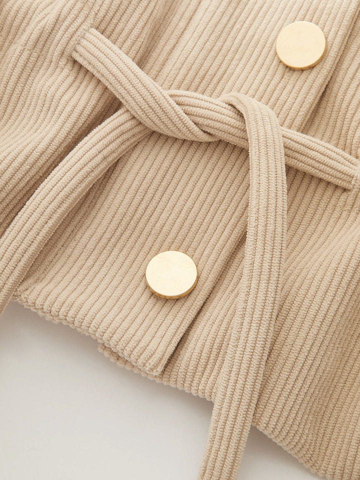 Detail of the drawstring tie and gold buttons on the apricot corduroy utility jacket
