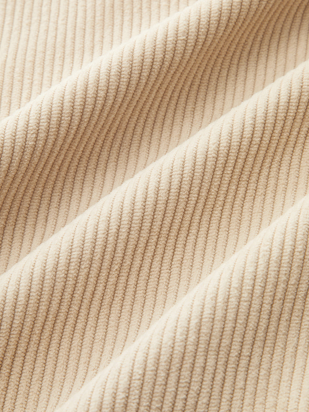 Close-up of fine beige corduroy fabric showing the soft vertical ribbing