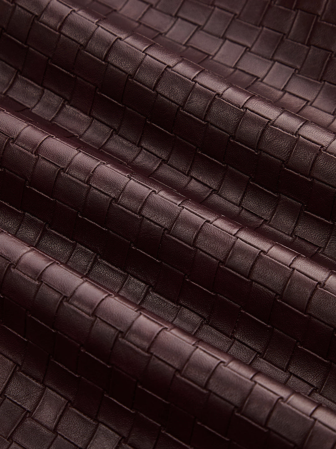 Texture detail of the intrecciato style basketweave in wine red faux leather
