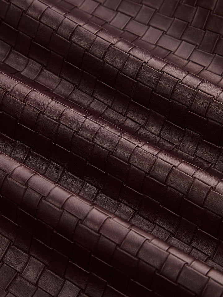 Texture detail of the intrecciato style basketweave in wine red faux leather