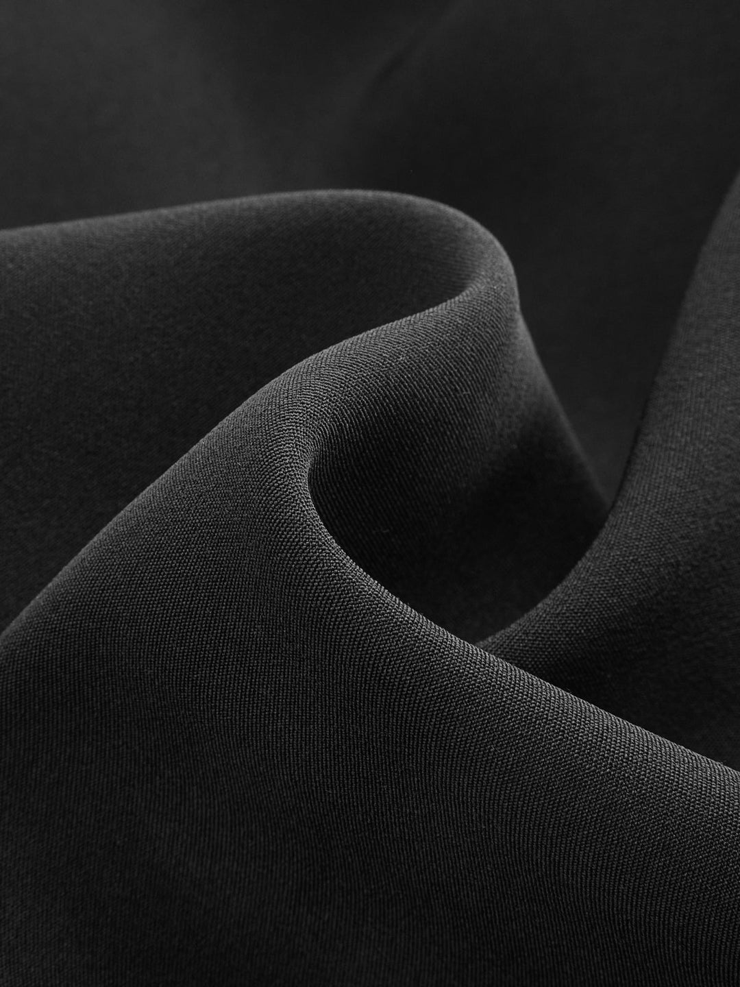 Fabric detail showing the smooth matte black suiting weave of the military jacket