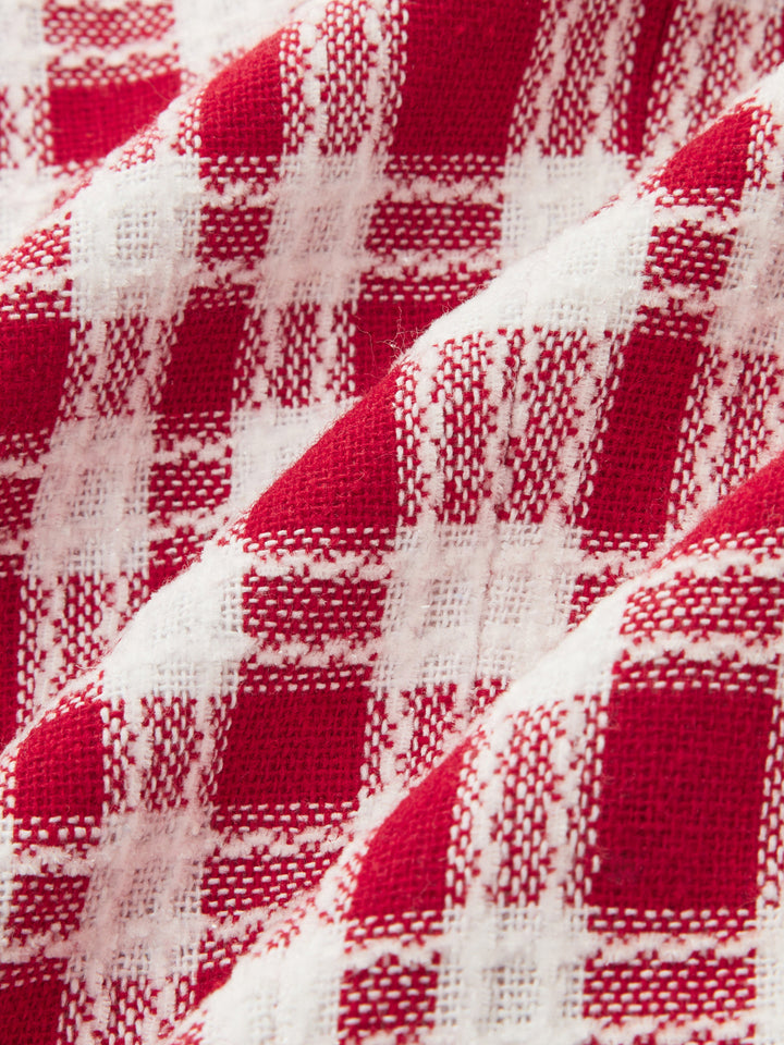 Close-up of the red and white woven check tweed fabric of the belted vest