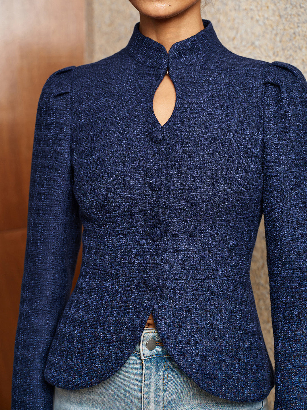 Close-up of the keyhole cut-out and covered buttons on the navy textured tweed jacket