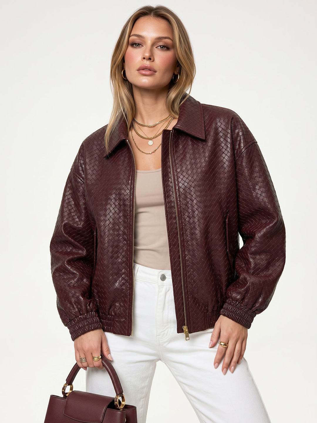 Model in burgundy woven faux leather bomber jacket with white jeans and matching handbag