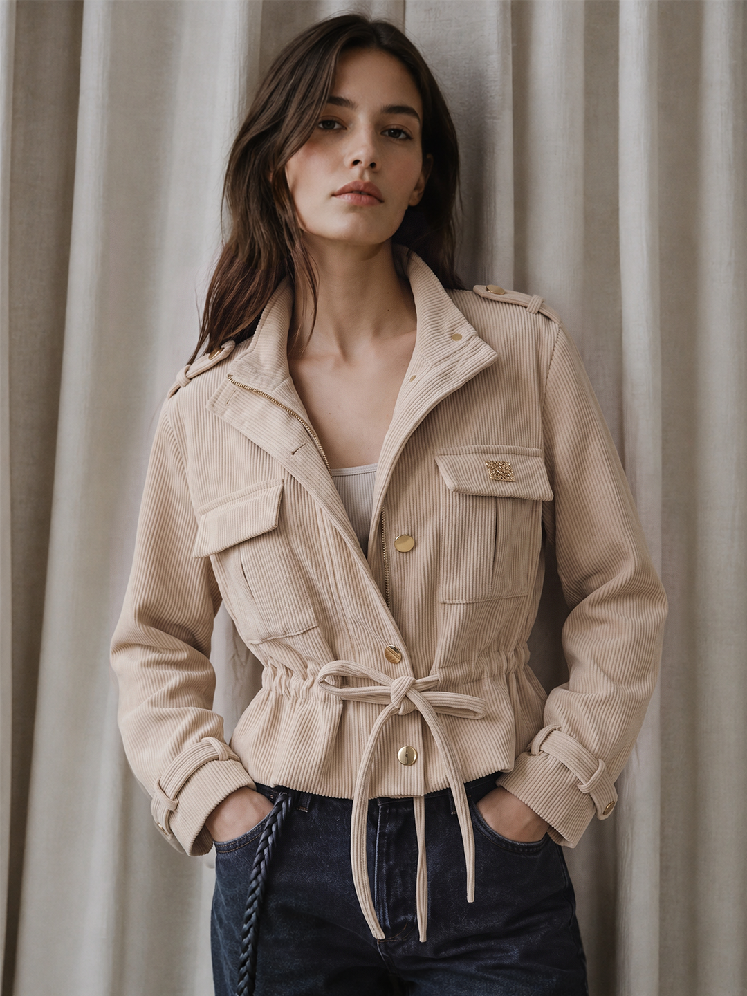 Model in a beige corduroy cropped utility jacket with drawstring waist and jeans