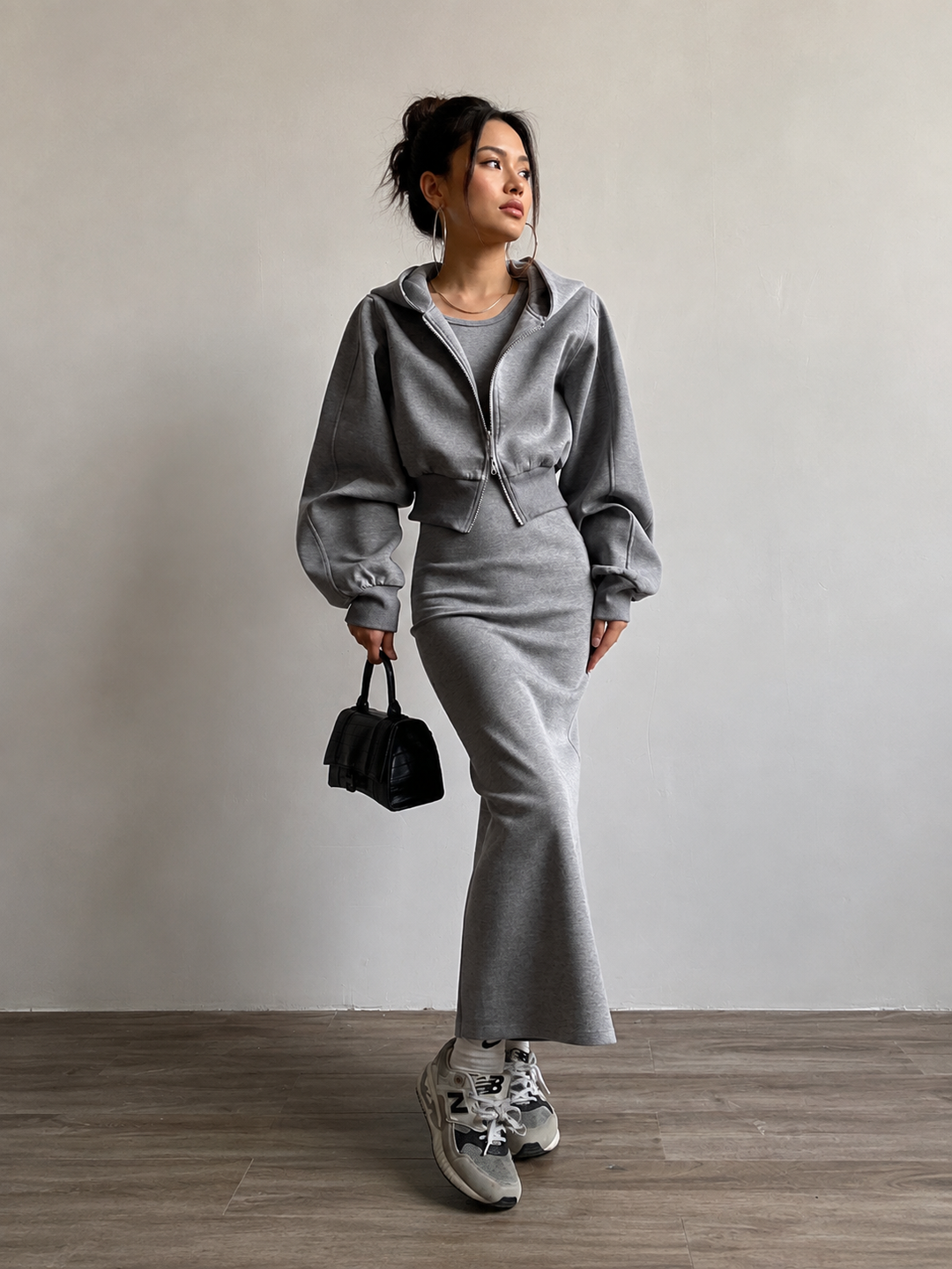 Walking shot of the grey hoodie and skirt co-ord with black mini bag