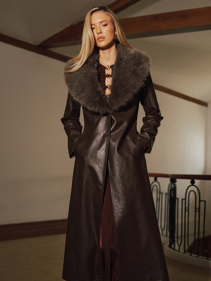 Front view of the maxi length brown faux leather coat with fur collar and tie belt