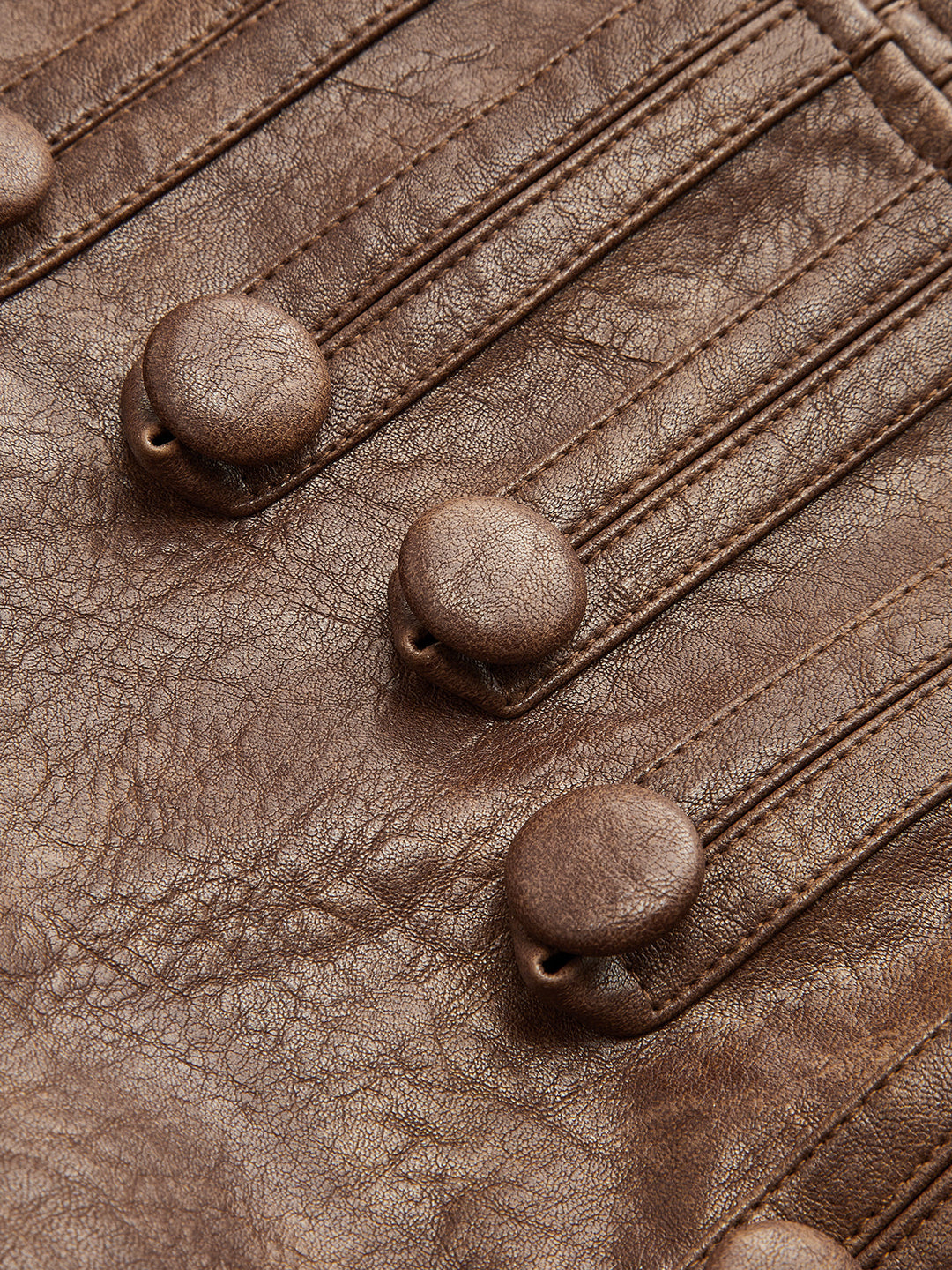 Close-up of antique dome buttons on brown faux leather Napoleon style jacket