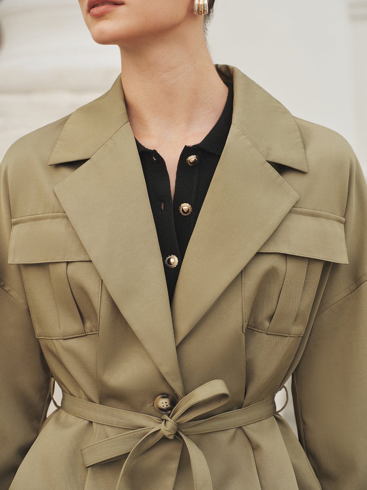 Close-up of the wide lapel collar and self-tie belt knot on khaki fabric