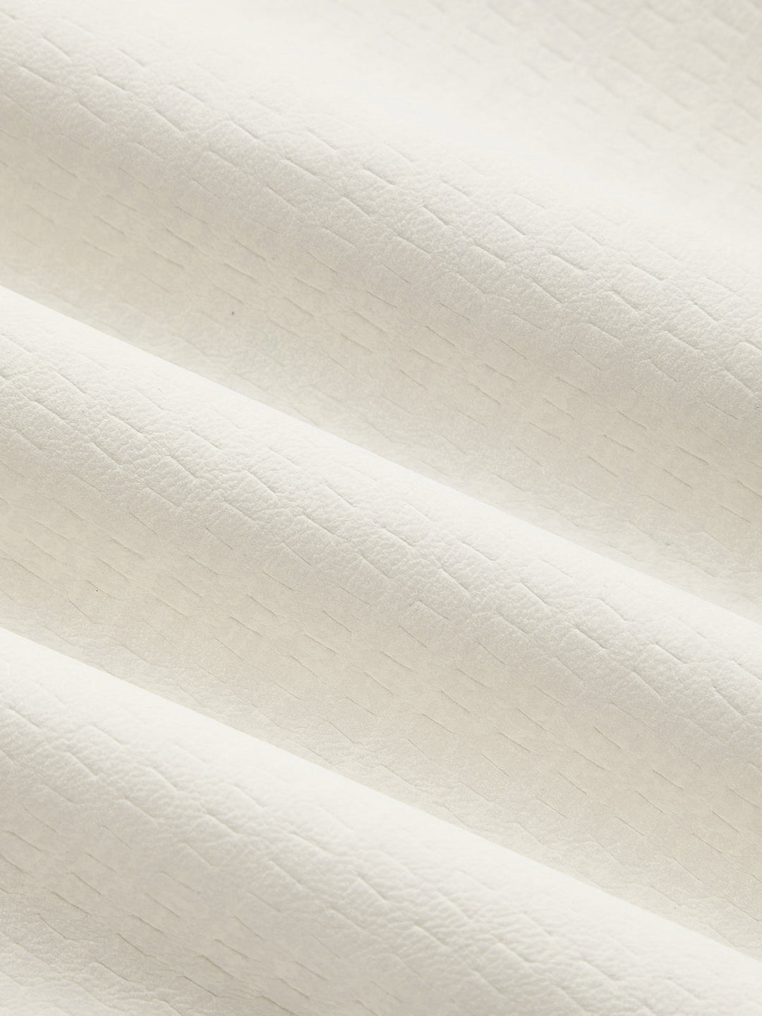 Texture detail of the soft matte ivory faux leather fabric
