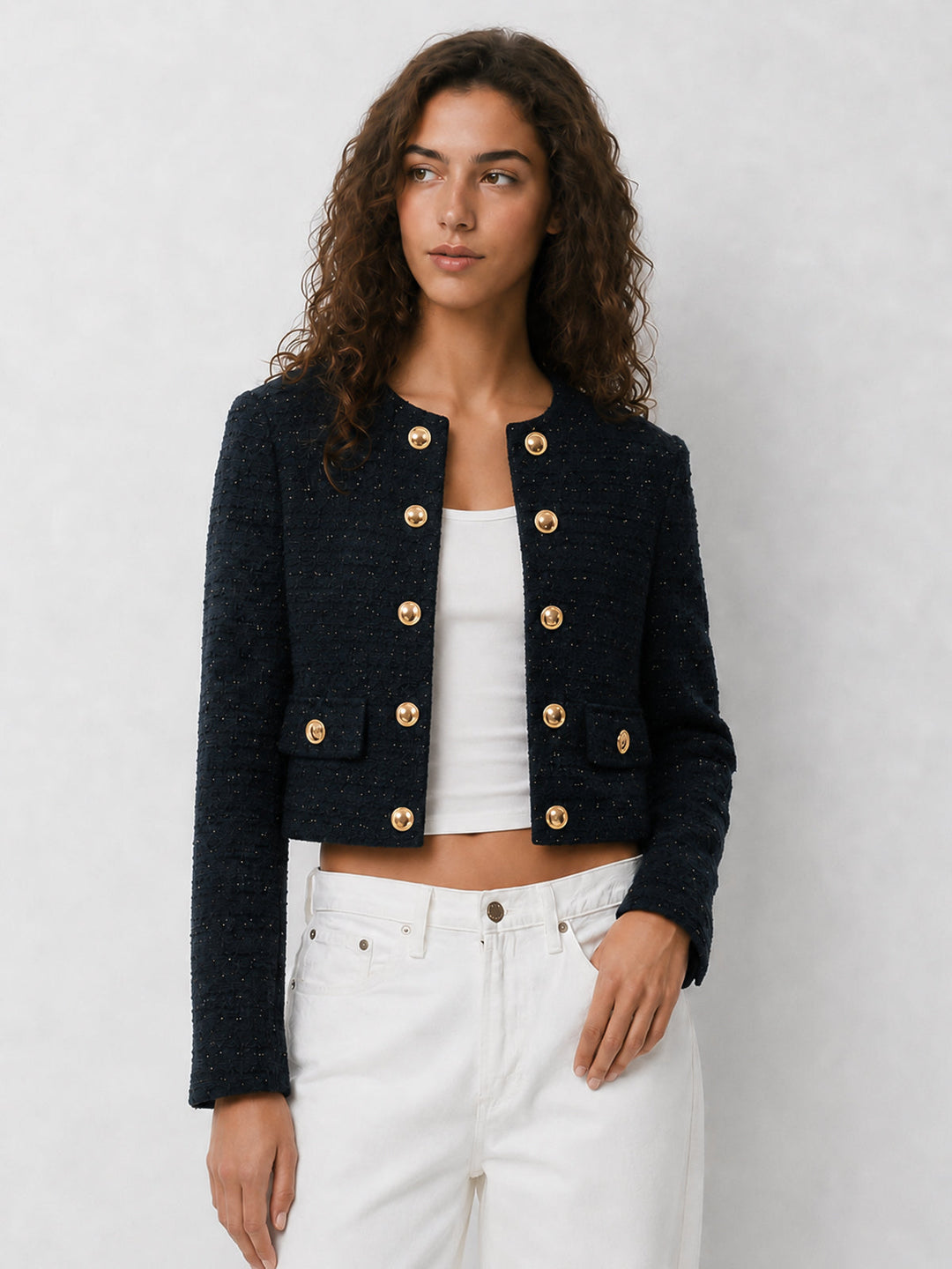 Woman in the navy boucle jacket worn open over a white top and cream wide leg jeans
