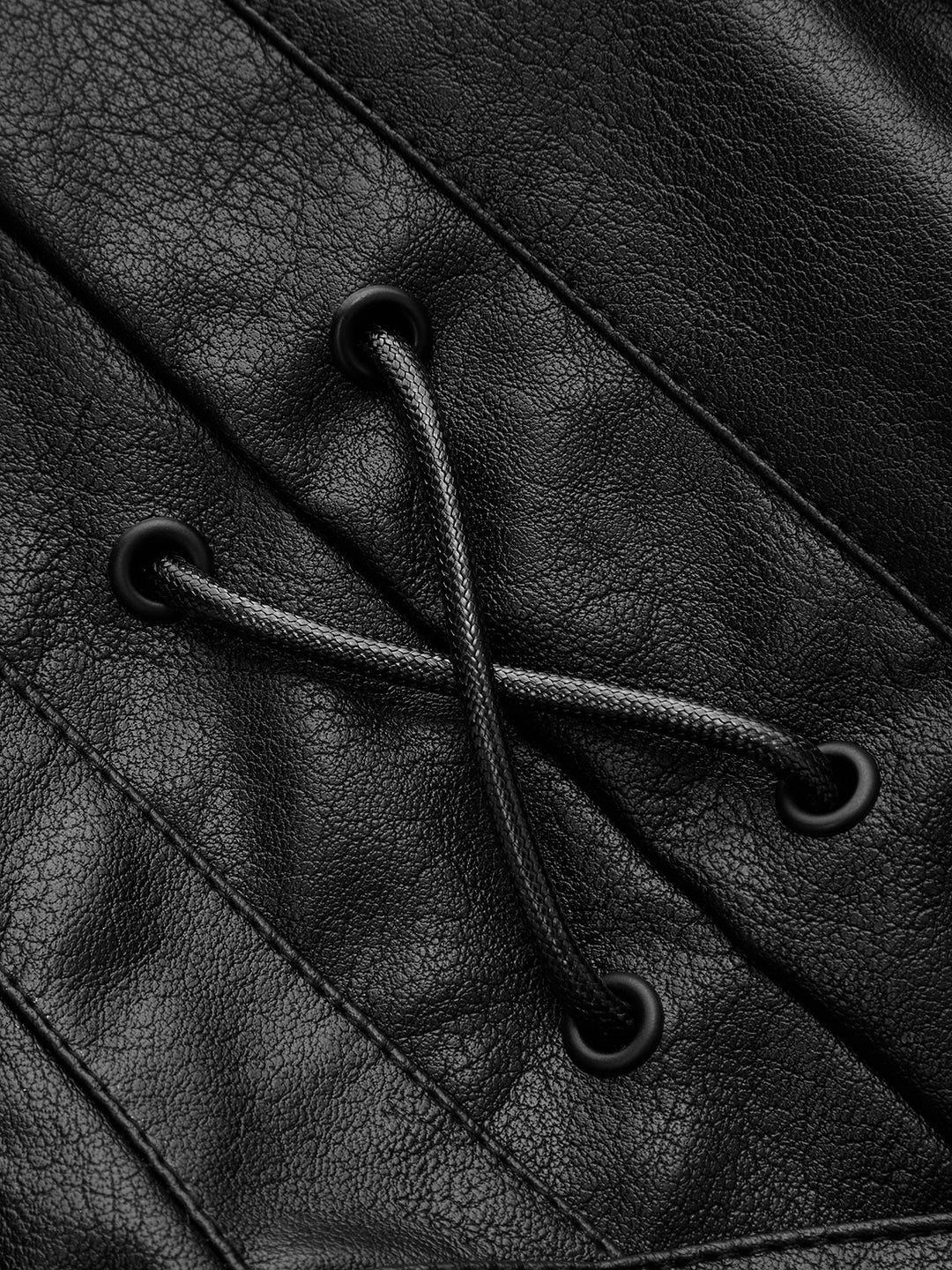 Close-up of the cord lacing and matte eyelets on the shoulder of the black jacket