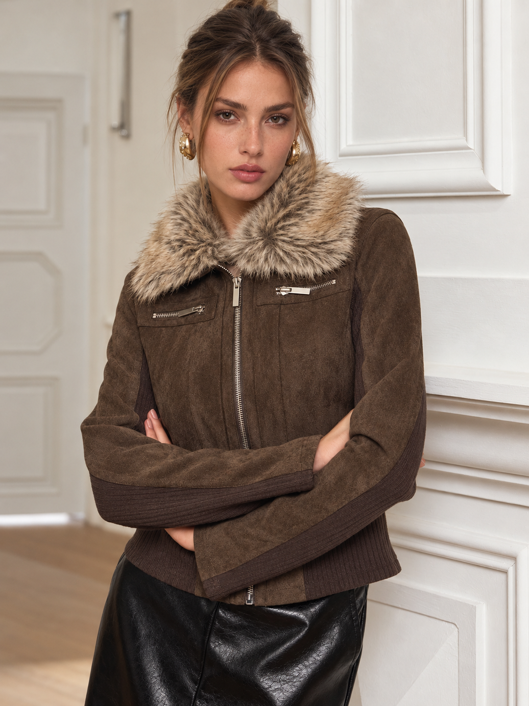 Woman with arms crossed wearing brown suede jacket with ribbed knit sleeve panels
