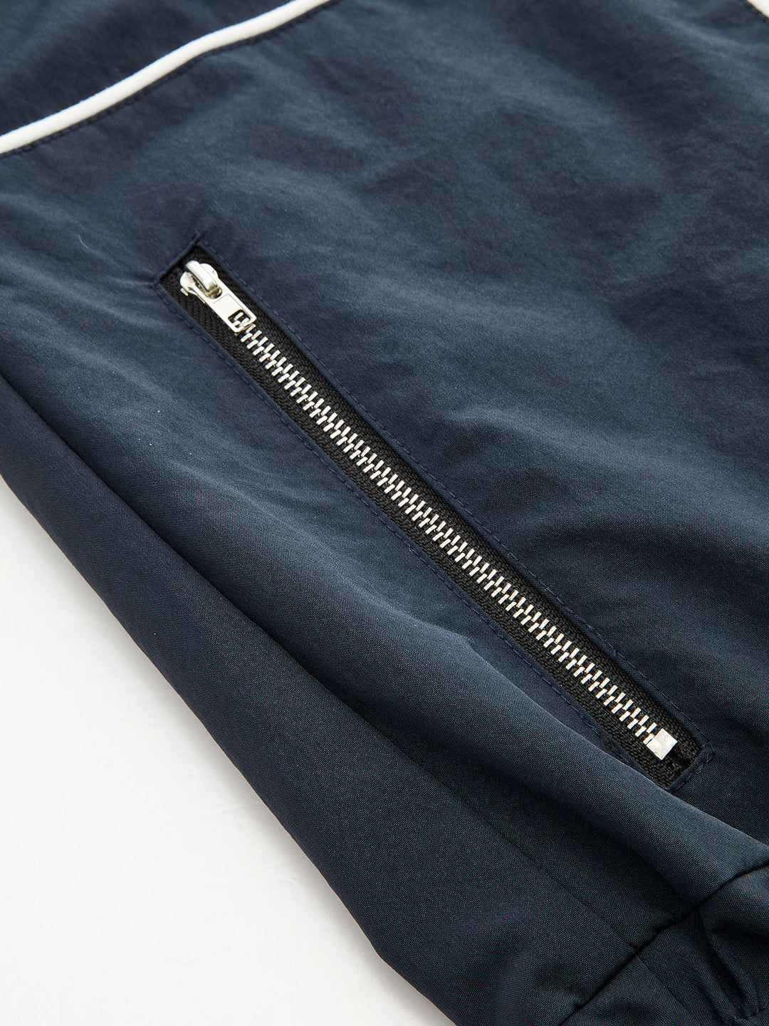 Close-up of the silver zip pocket and white contrast piping on navy fabric