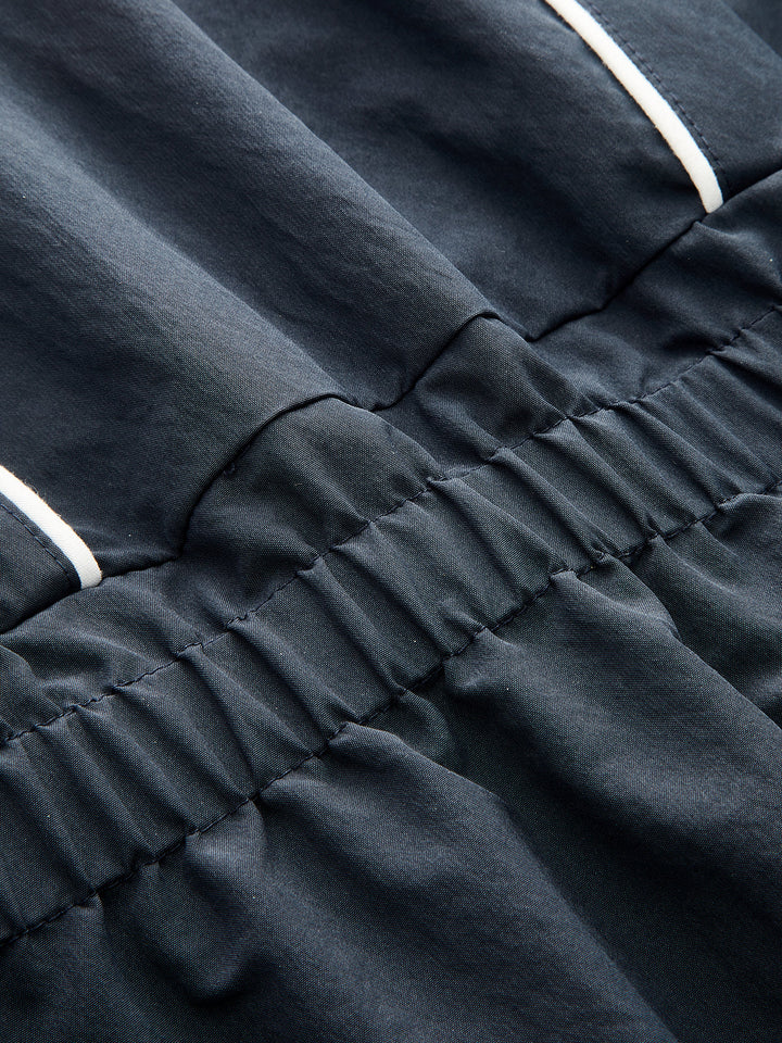 Detail of the elasticated gathered waistband on the navy contrast piping jacket