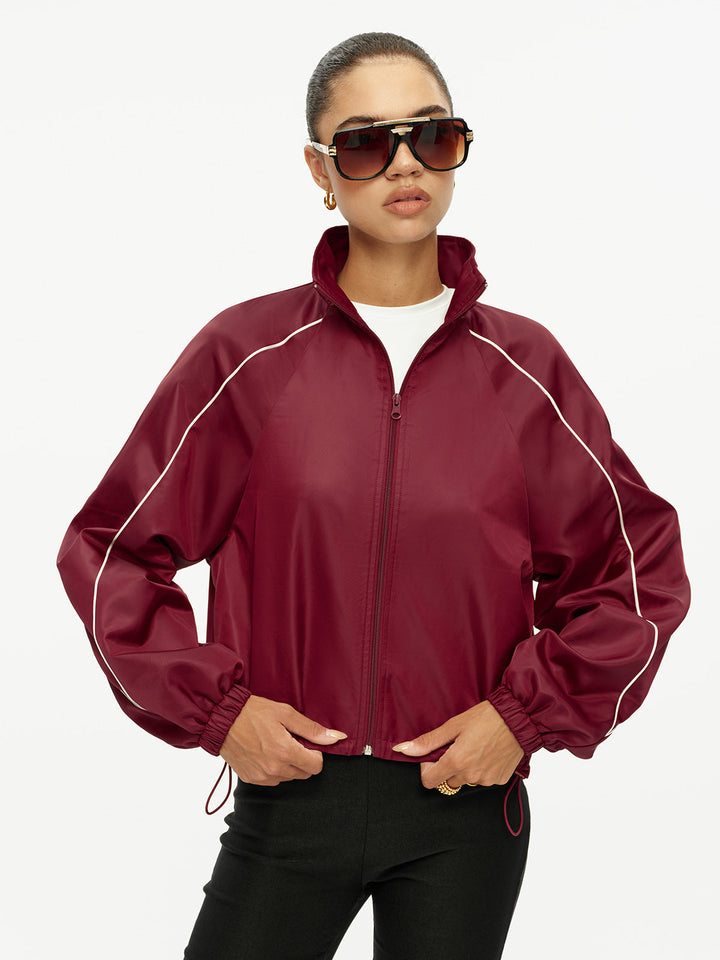 Burgundy track jacket worn zipped with hands in the side pockets