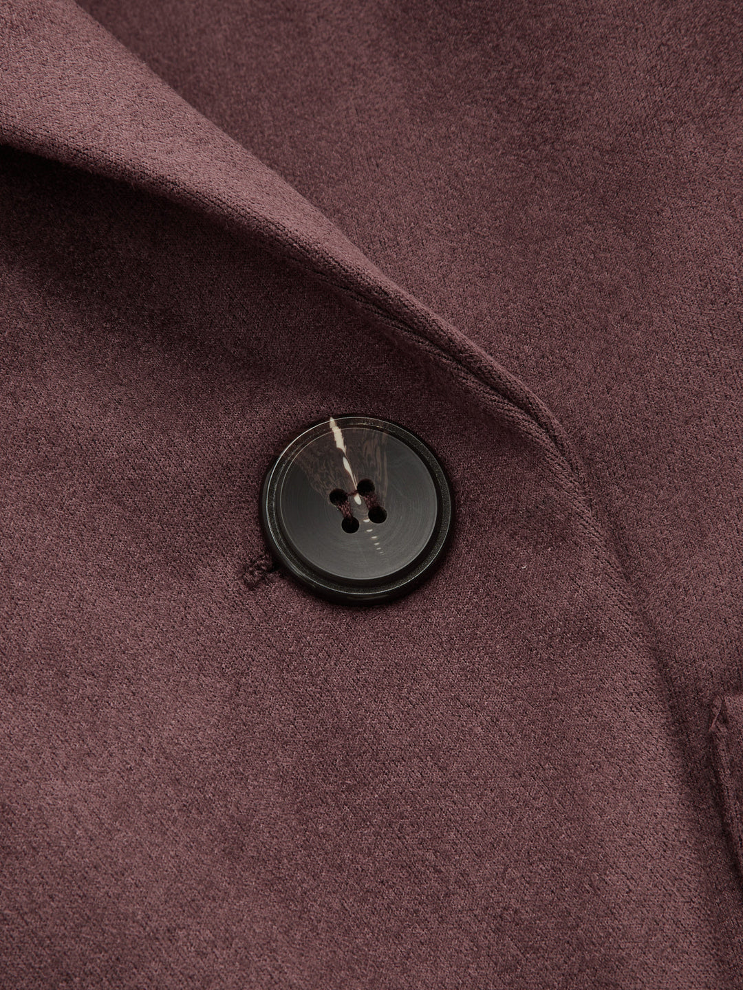 Close-up of the dark horn button and shawl collar on the burgundy faux suede jacket