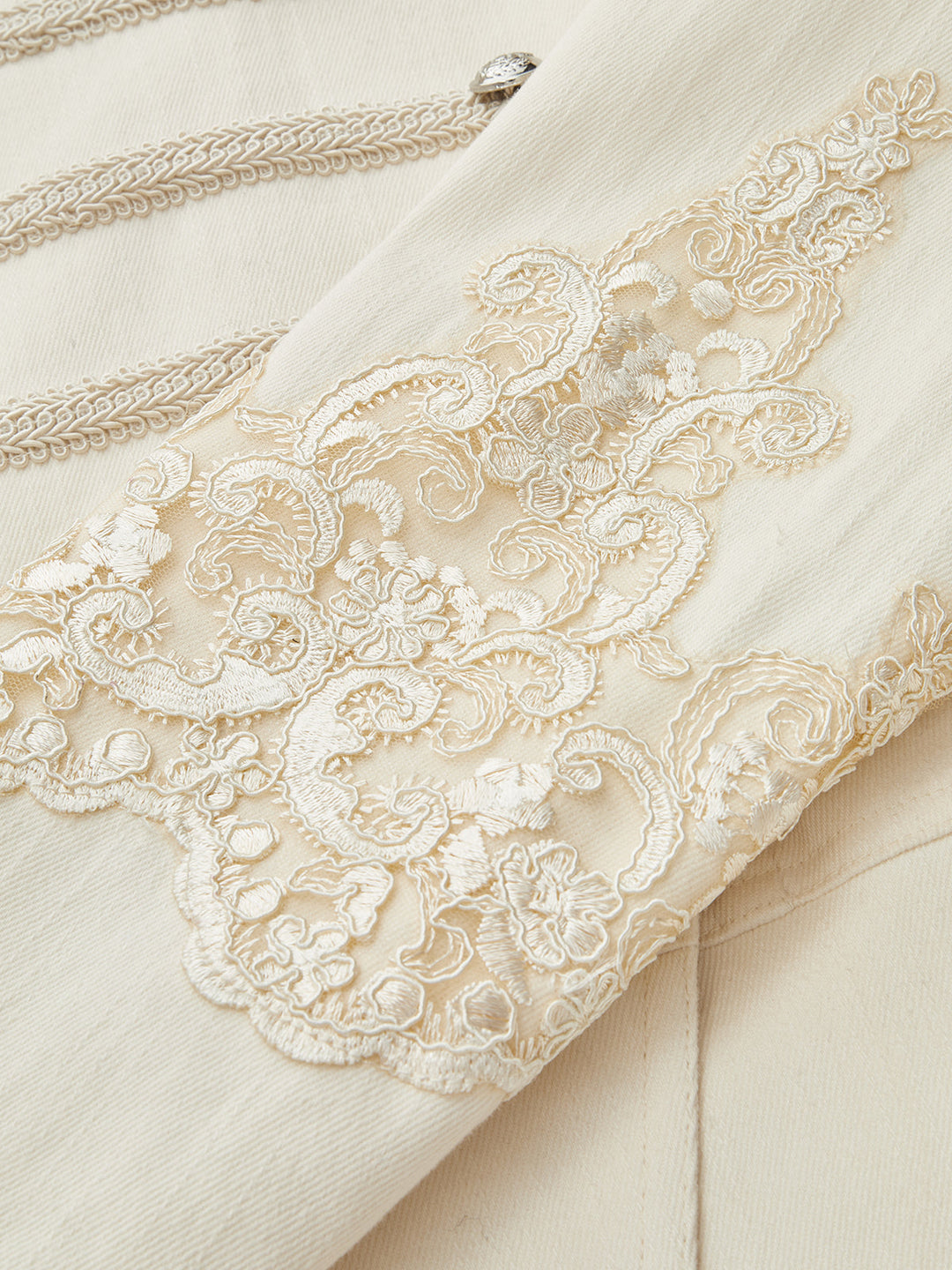 Detail of the cream floral lace applique on the sleeve of the military style jacket