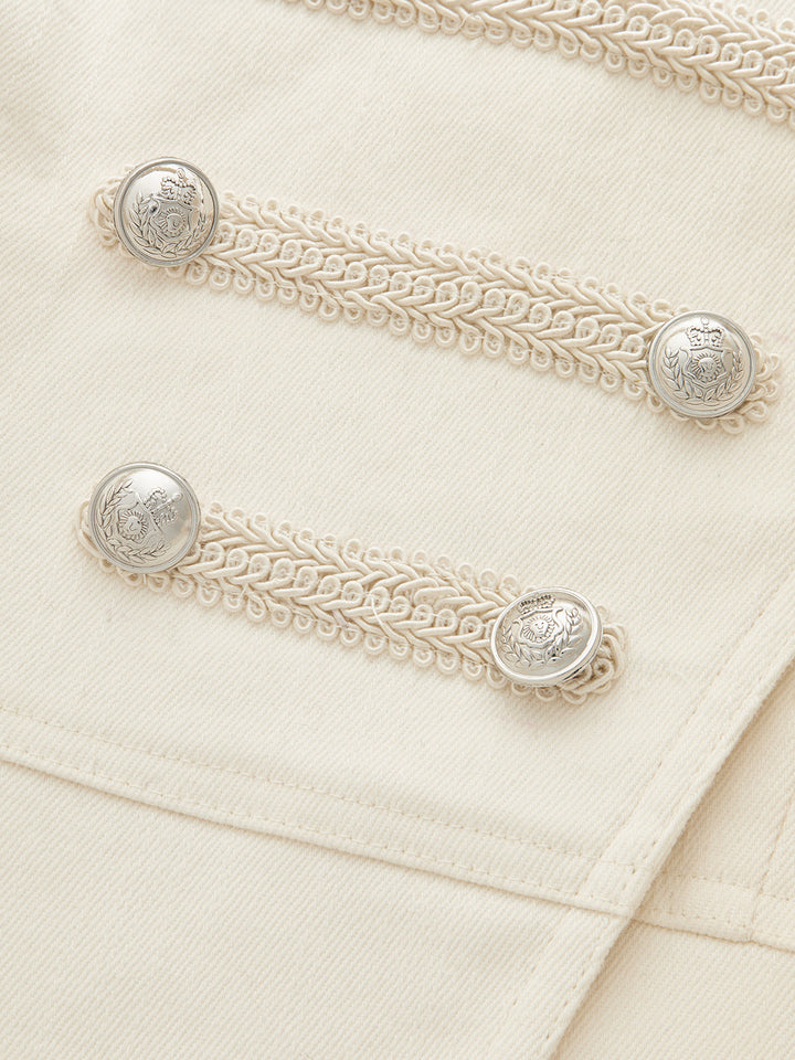 Macro of the silver crest buttons and braided cord trim on the ivory napoleon jacket