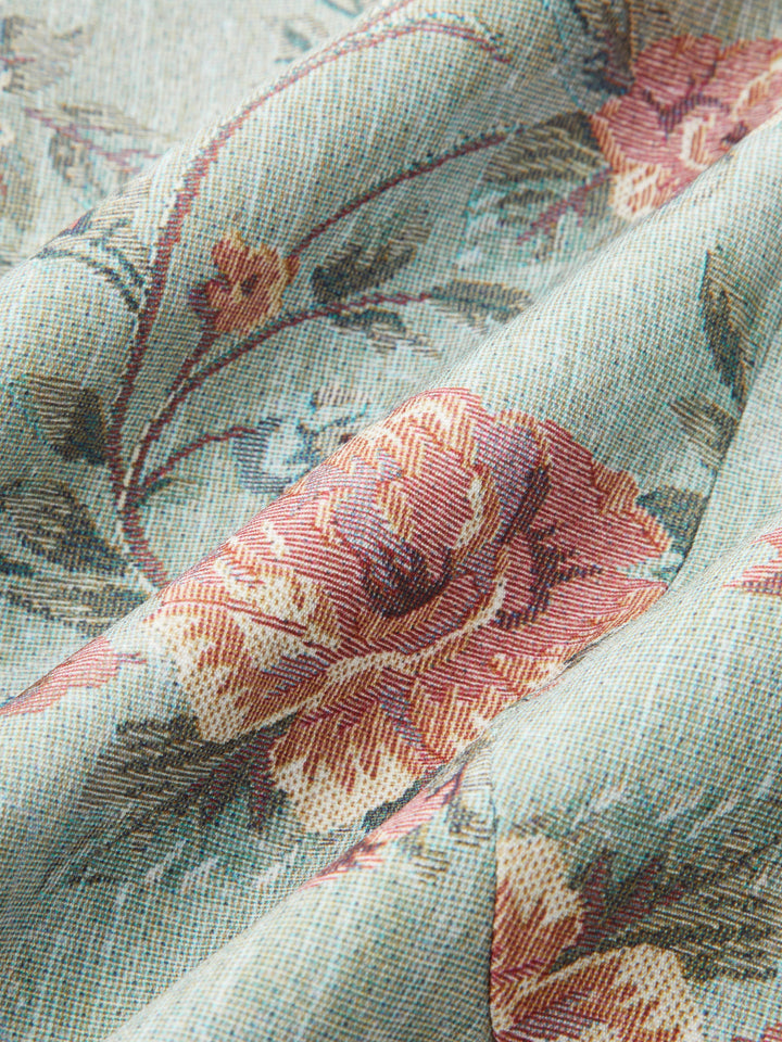 Macro of woven floral tapestry fabric with pink roses on a soft sage background