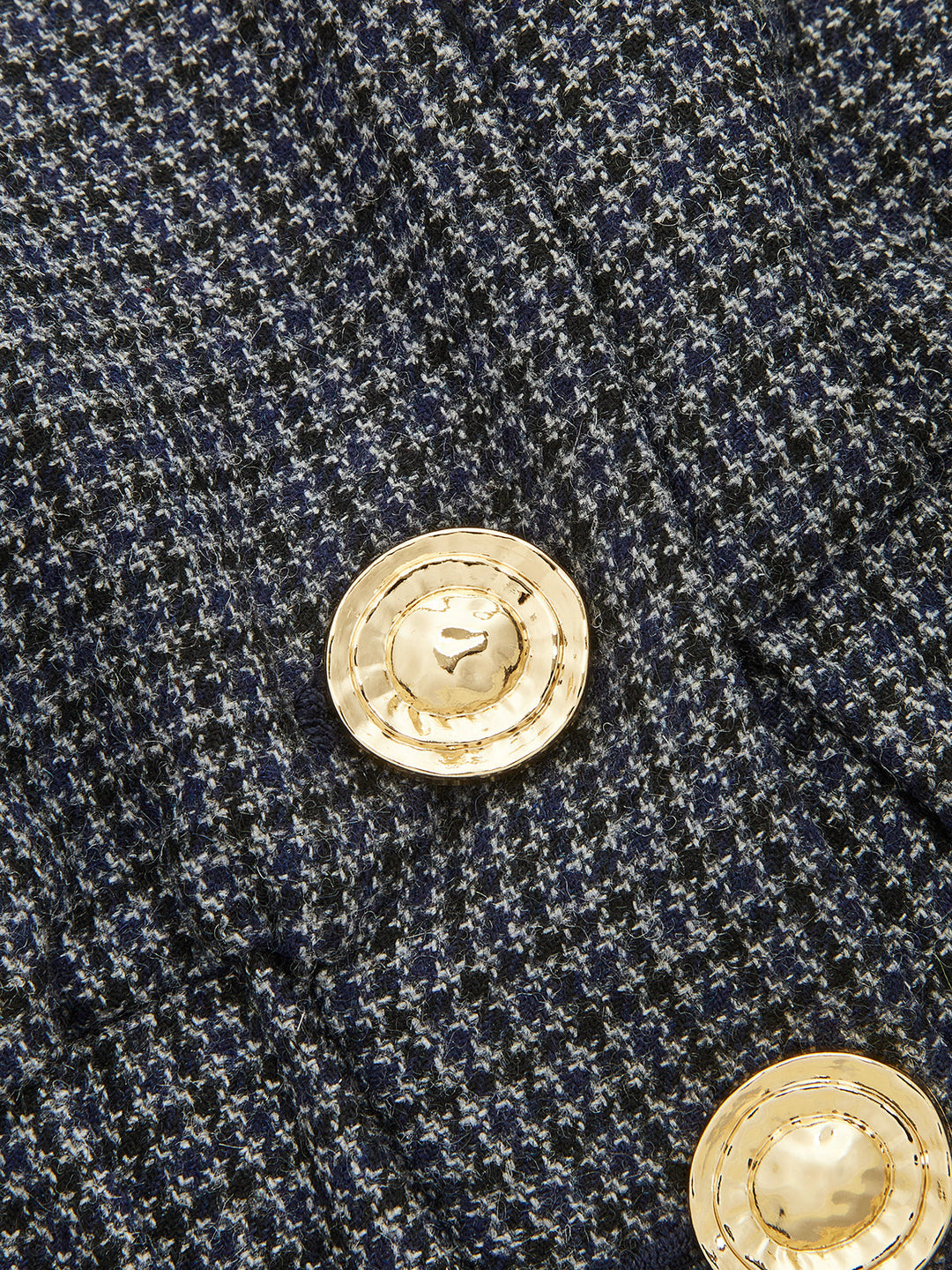 Close-up of the ornate gold buttons on the grey houndstooth weave