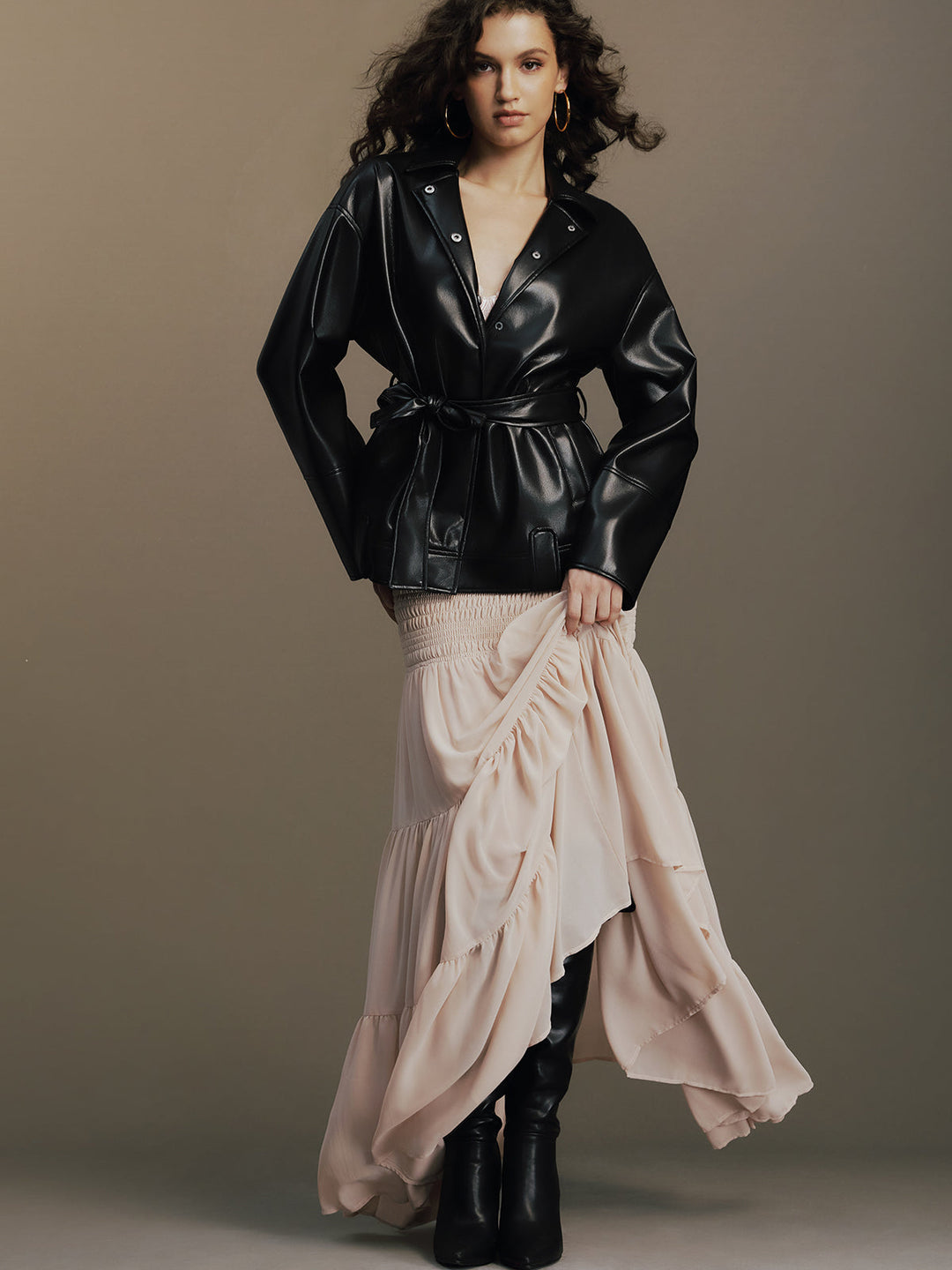 Model with hands on hips in the black belted jacket, collar popped open