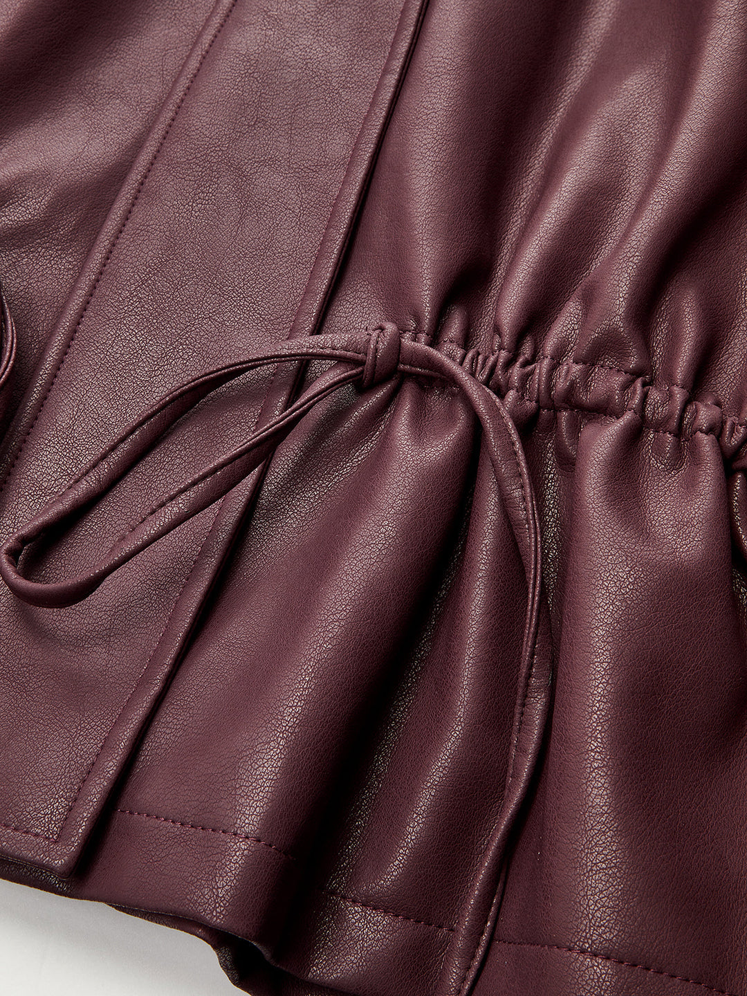 Detail of the drawstring cord and elasticated waist on burgundy faux leather