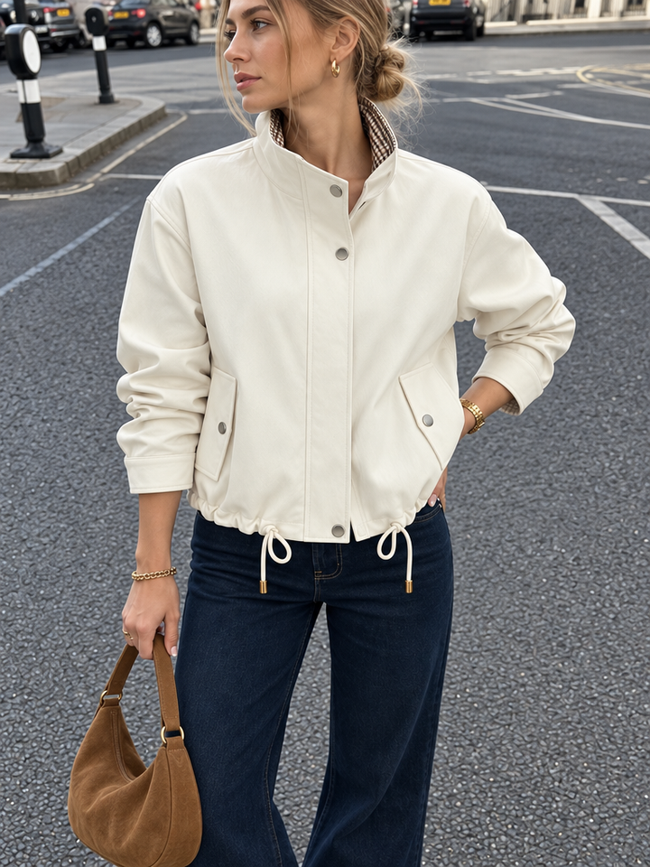 Street style front view of cream drawstring-waist bomber jacket with stand collar and dark denim