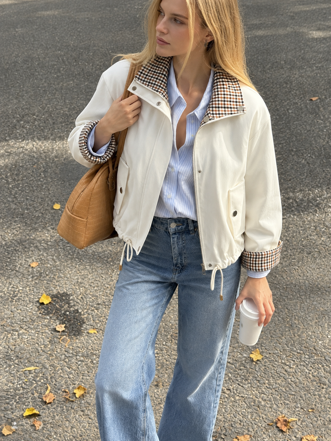 Model in cream reversible check jacket, open over blue shirt and wide-leg jeans, tan shoulder bag