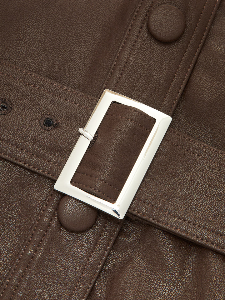 Close-up of the silver rectangular belt buckle and covered buttons on brown leather