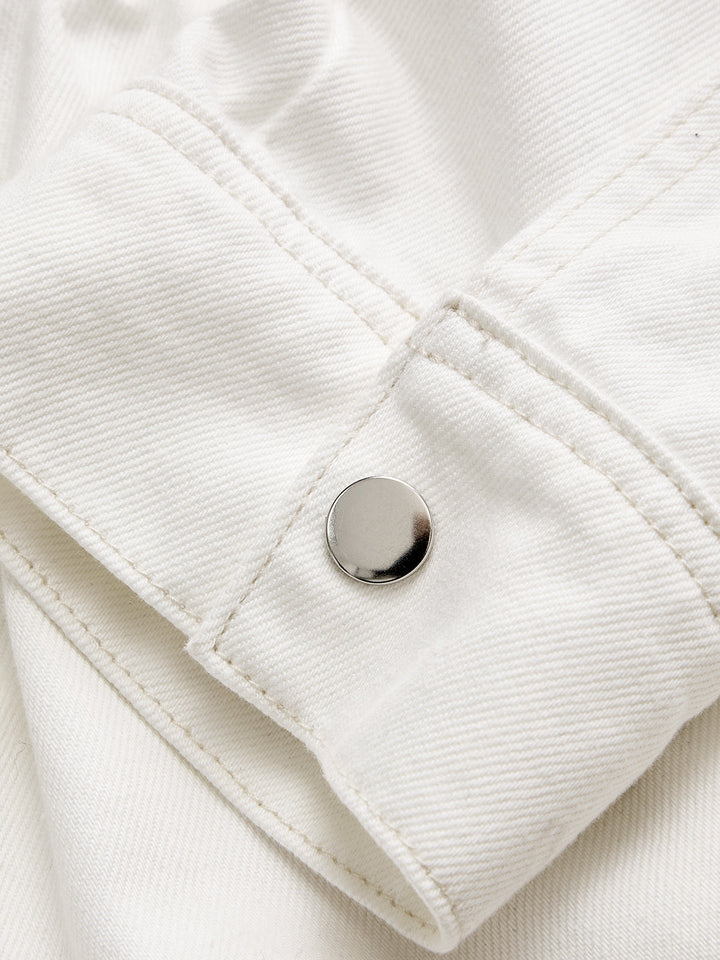 Detail of polished silver snap button on the buttoned cuff of a white denim jacket