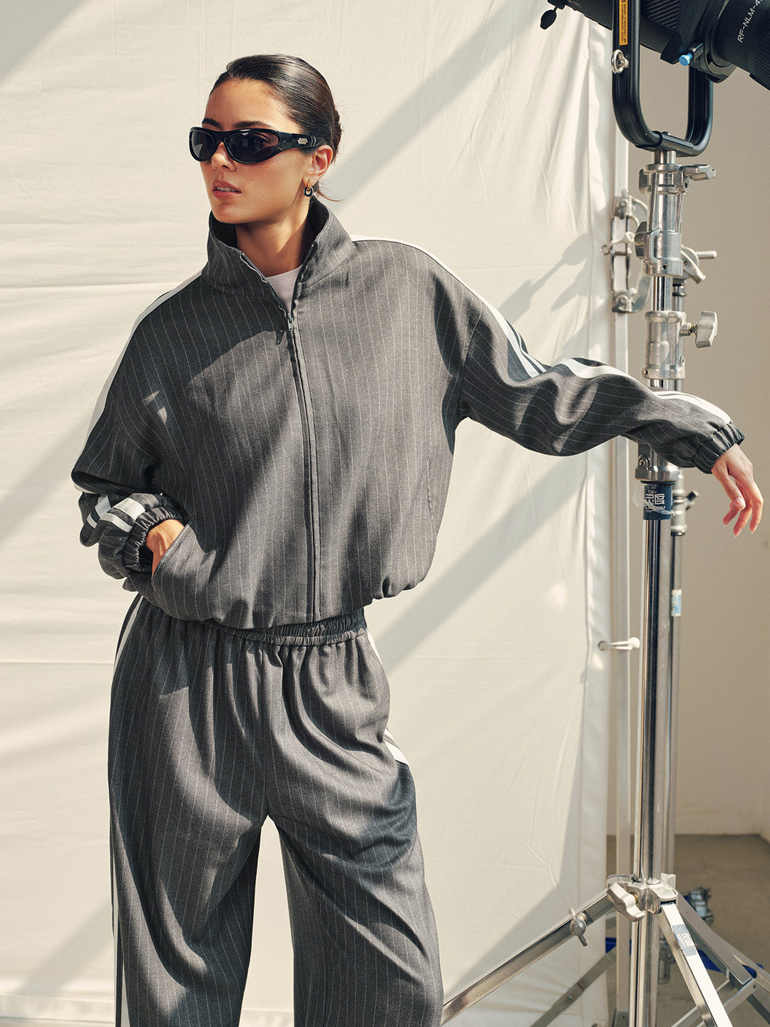 Model with arm outstretched in the grey striped zip jacket showing the relaxed drop shoulder