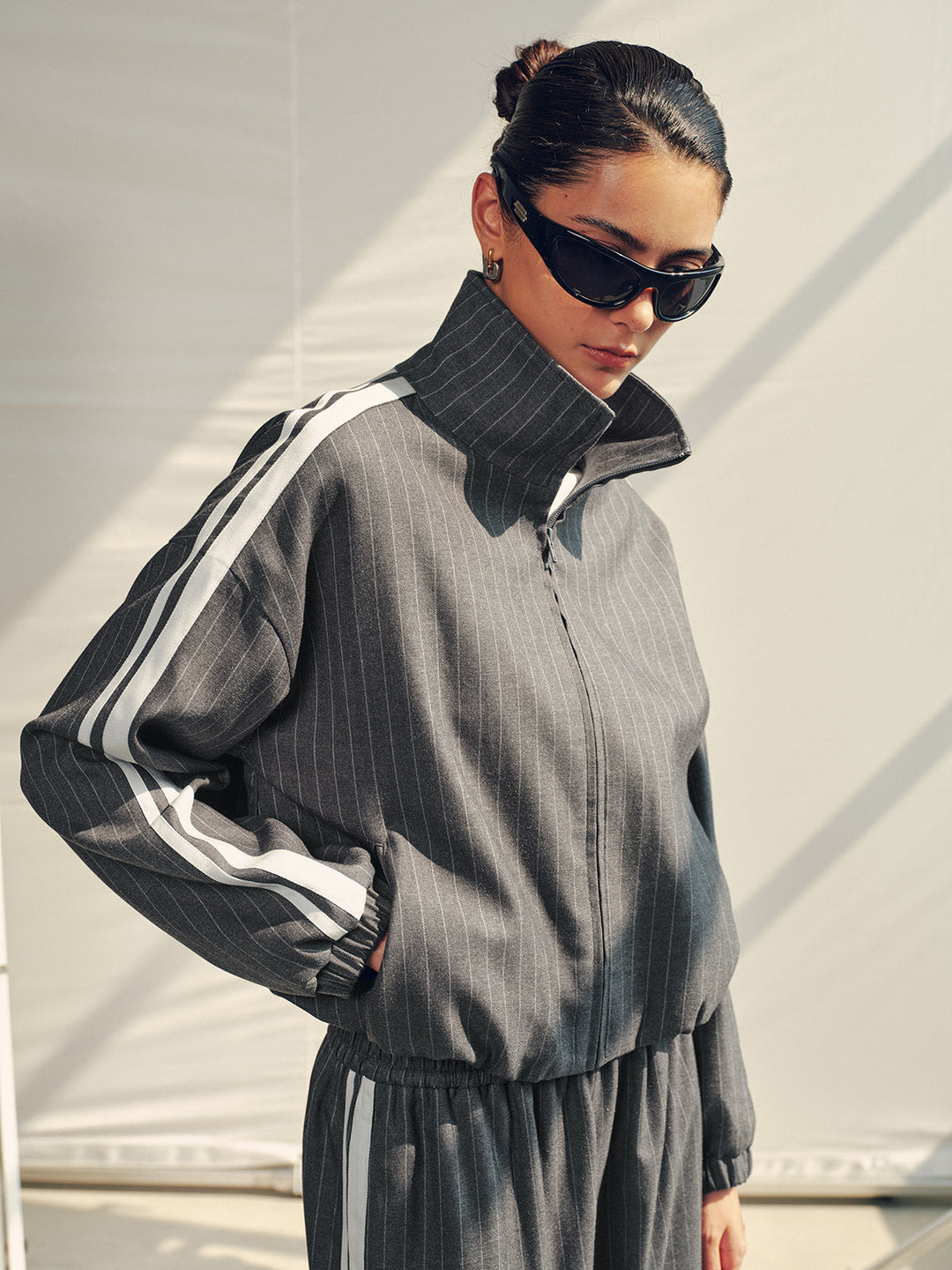 Grey pinstripe track jacket with white side stripe, worn with matching wide leg trousers