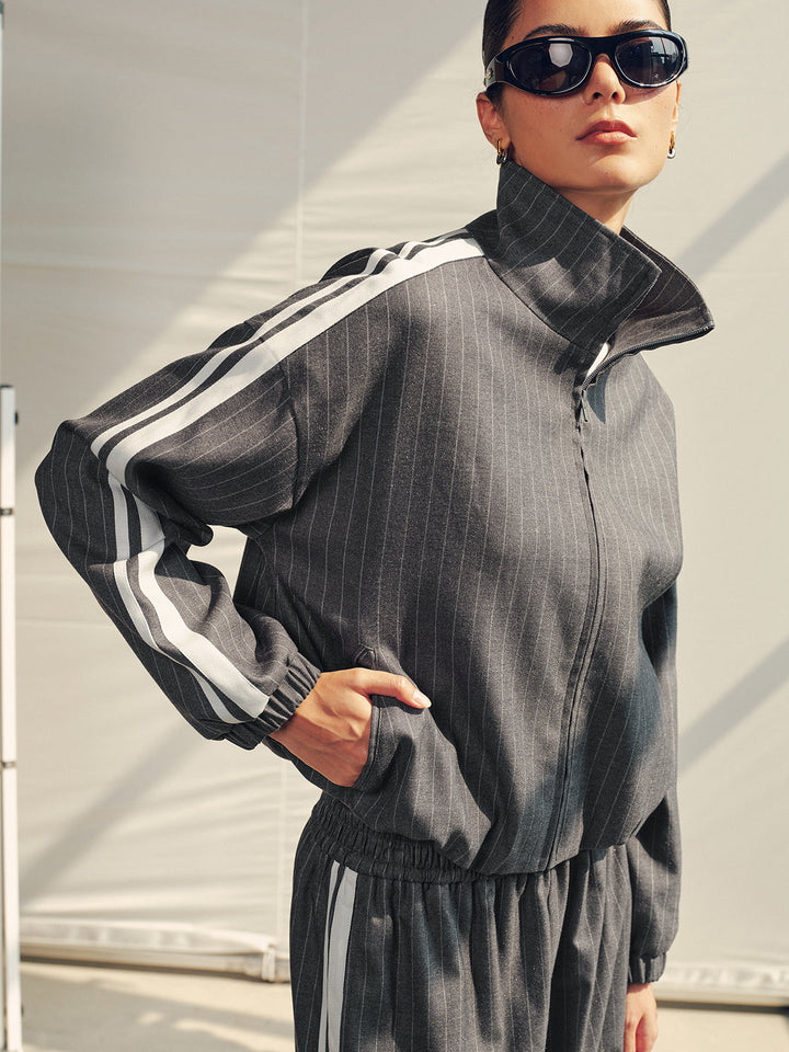 Side view of the zip up pinstripe jacket showing the contrast sleeve stripe and elastic hem