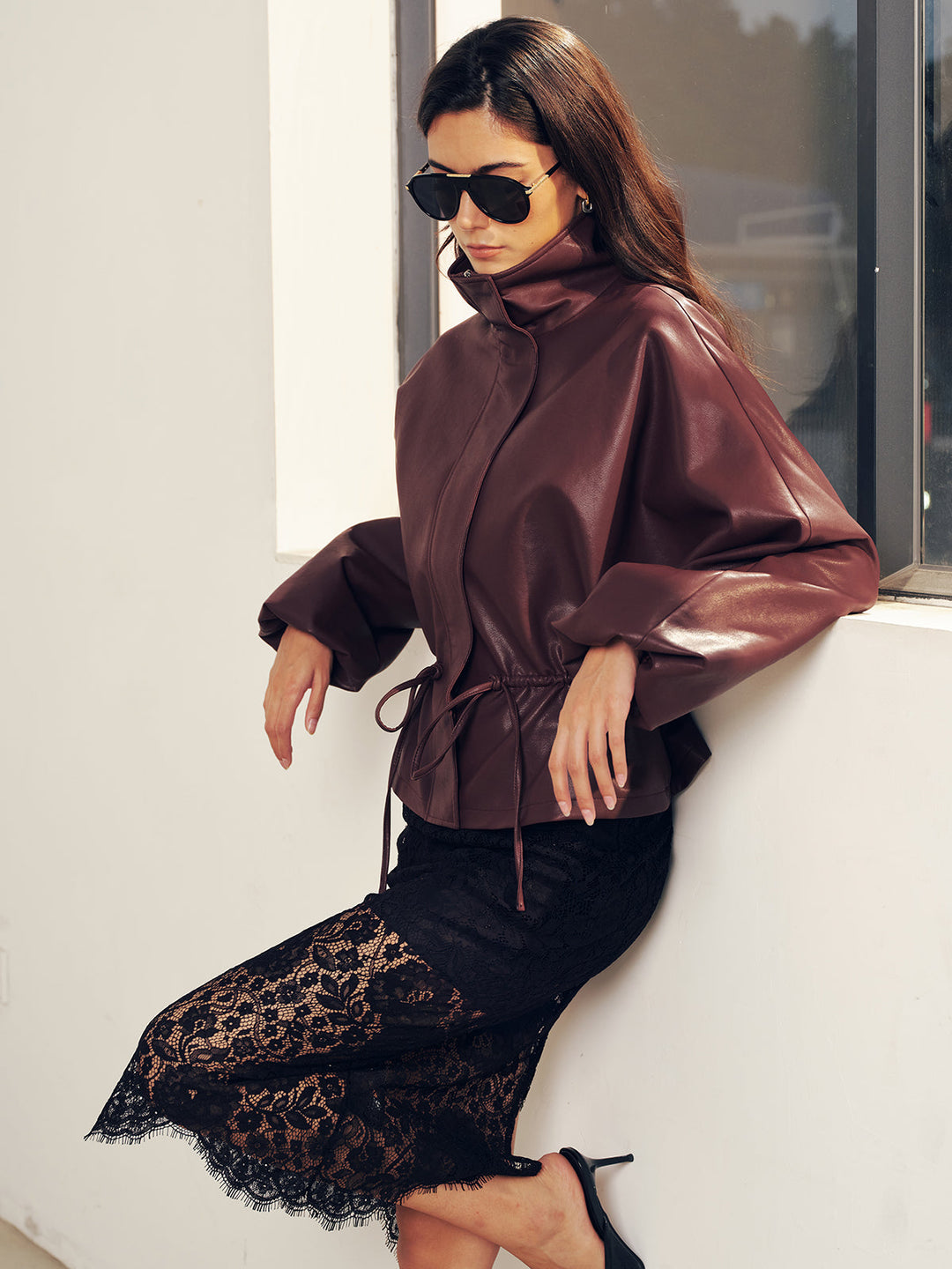 Side street style view of burgundy cropped jacket with drawstring tie hanging at the hem