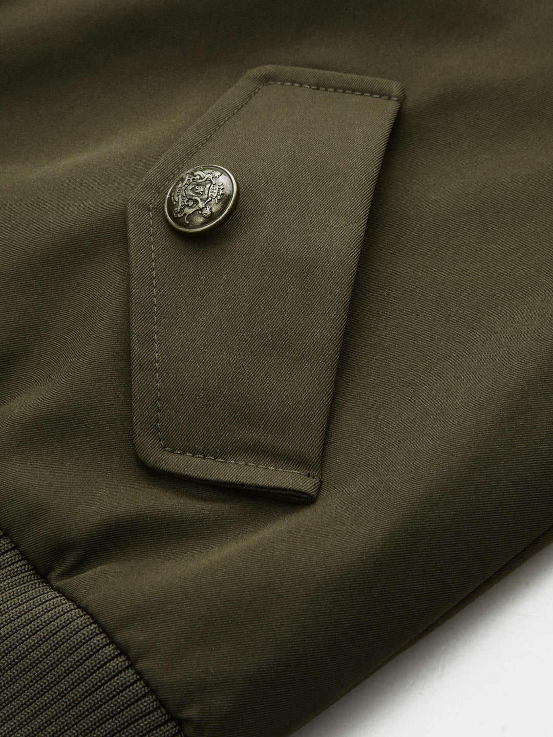 Close-up of engraved metal button on the flap pocket of the green bomber jacket