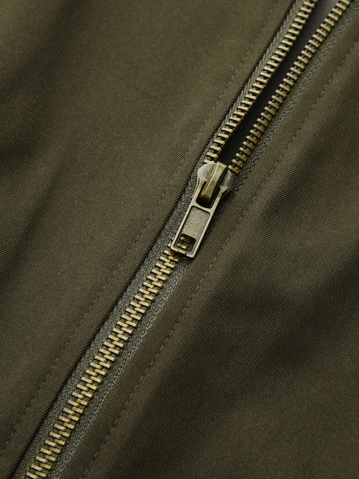 Detail of the antique gold front zip on olive bomber jacket fabric