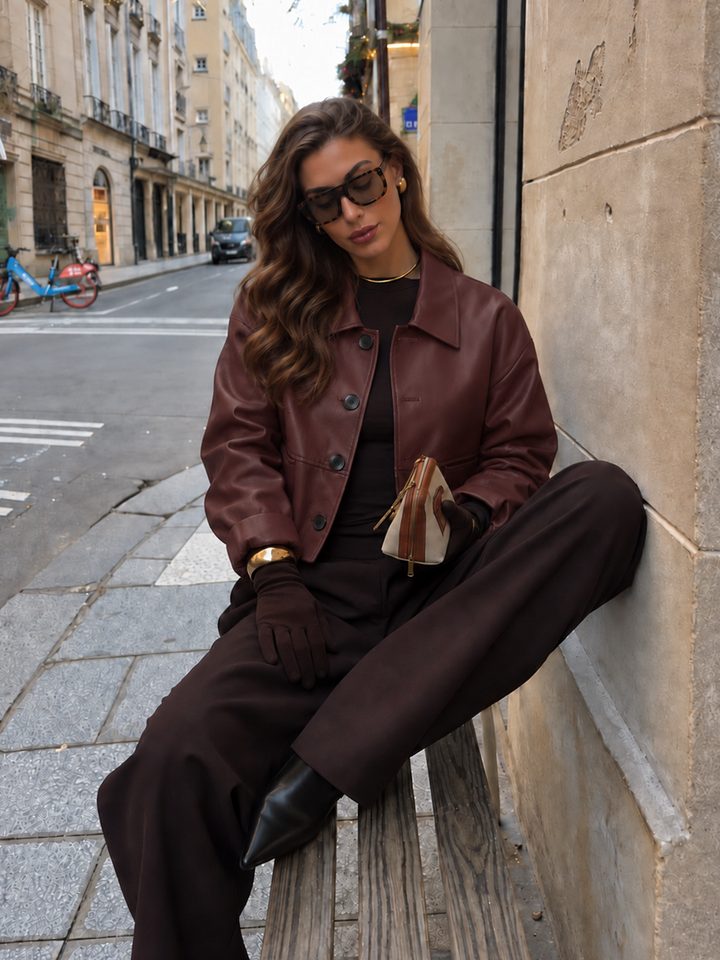 Seated street style shot of boxy wine red leather look jacket with button front