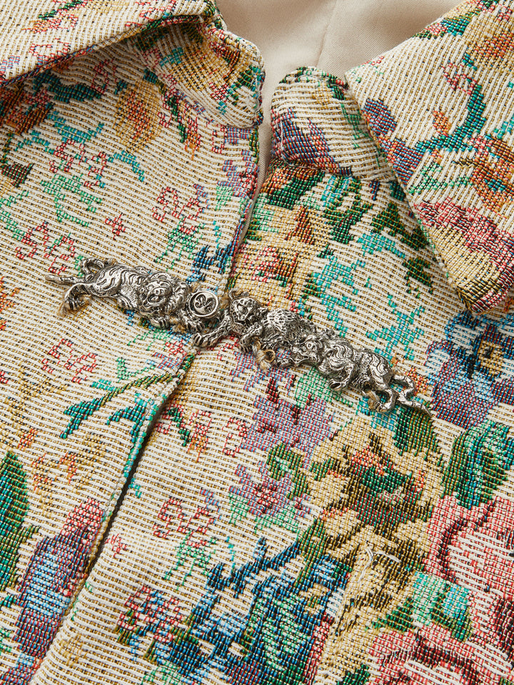 Close-up of the silver filigree frog button fastening on floral brocade fabric