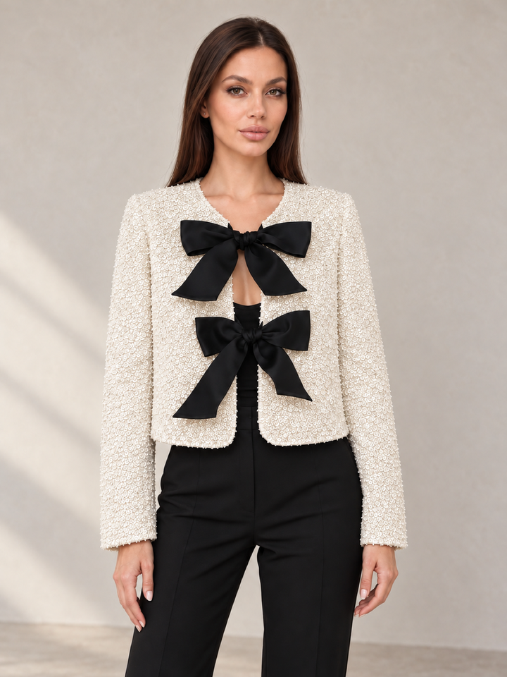 Cream sequined jacket with black satin bows, worn open over black trousers