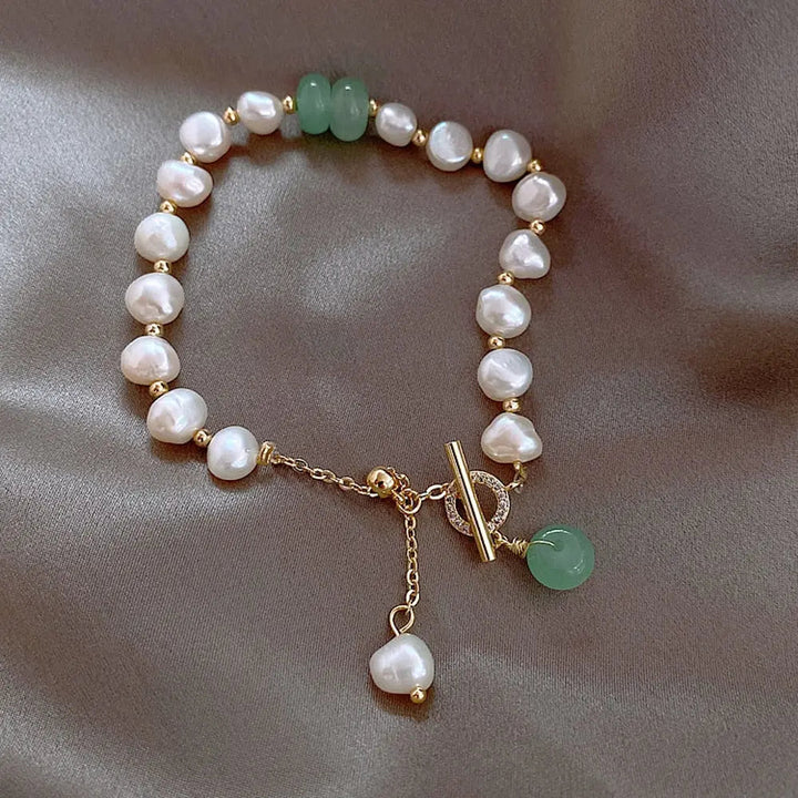 Natural pearl and jade beaded bracelet coiled on a flat surface